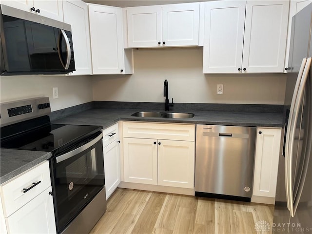 kitchen featuring stainless steel appliances, white cabinetry, sink, and light wood-type flooring