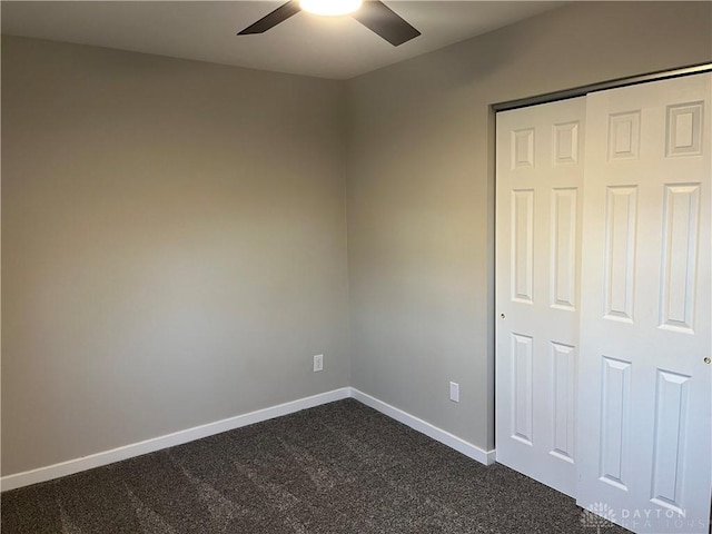 unfurnished bedroom with ceiling fan, dark carpet, and a closet