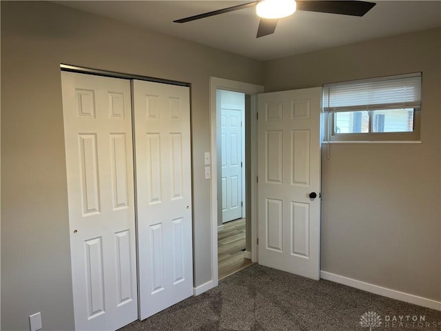 unfurnished bedroom featuring ceiling fan, dark carpet, and a closet