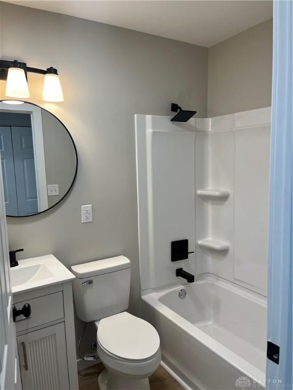 full bathroom with vanity, hardwood / wood-style floors,  shower combination, and toilet