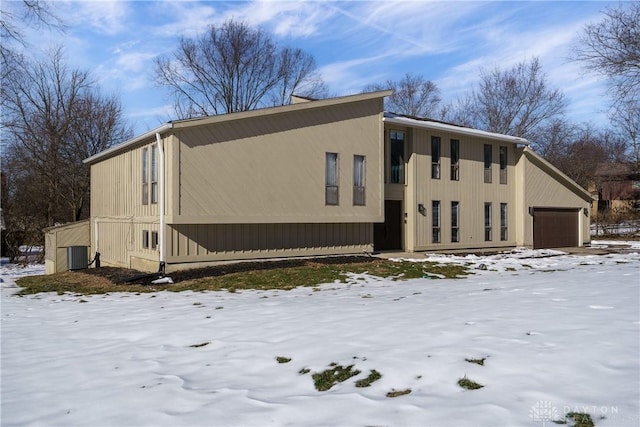 view of snow covered exterior featuring a garage and central AC