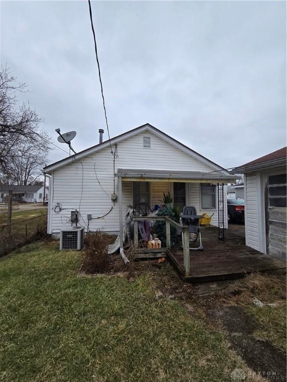 rear view of property featuring a lawn and central air condition unit