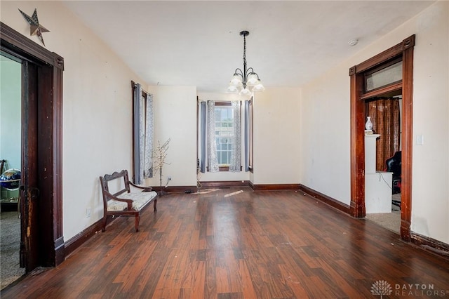 empty room featuring an inviting chandelier and dark hardwood / wood-style floors