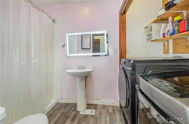 washroom with dark hardwood / wood-style flooring, sink, and washing machine and clothes dryer