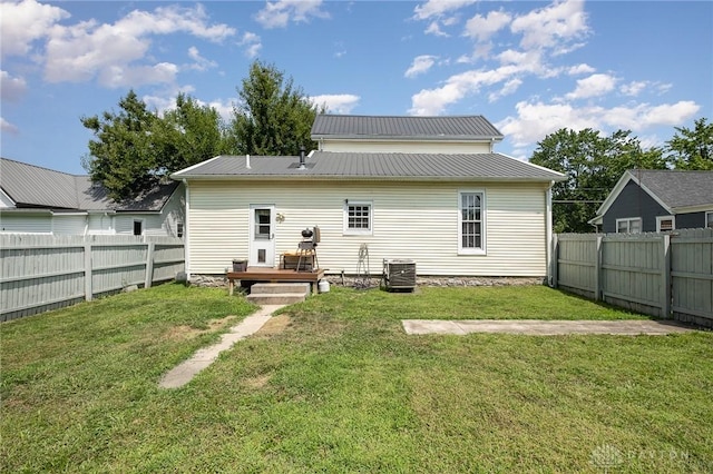 back of property featuring a wooden deck, a lawn, and central air condition unit