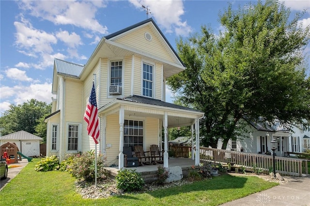 front of property with covered porch, a shed, and a front yard