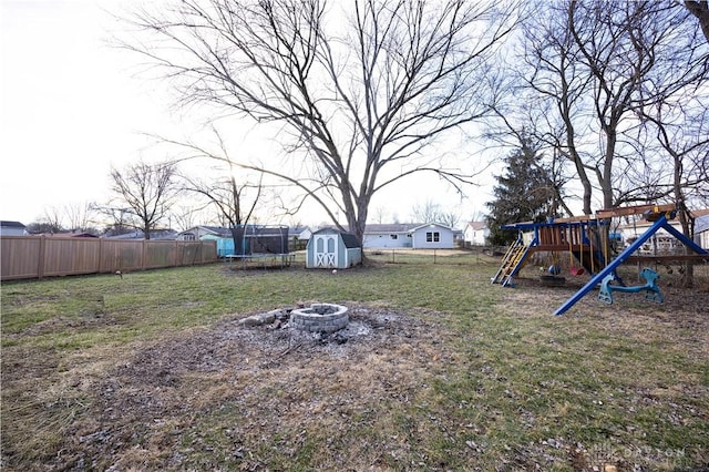 view of yard with a storage shed, an outdoor fire pit, a playground, and a trampoline