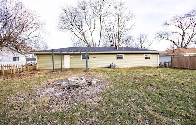 back of house with an outdoor fire pit, a yard, and central air condition unit