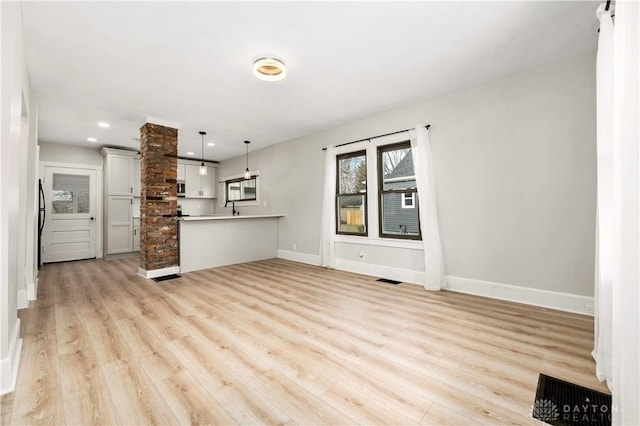 unfurnished living room featuring sink and light wood-type flooring