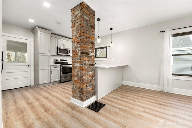 kitchen with light hardwood / wood-style flooring, stainless steel appliances, a healthy amount of sunlight, and ornate columns