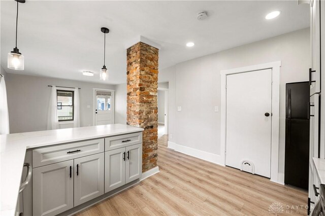 kitchen with black fridge, gray cabinetry, light hardwood / wood-style floors, and decorative light fixtures