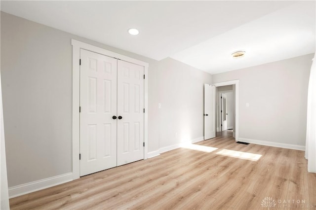 unfurnished bedroom with light wood-style floors, a closet, and baseboards