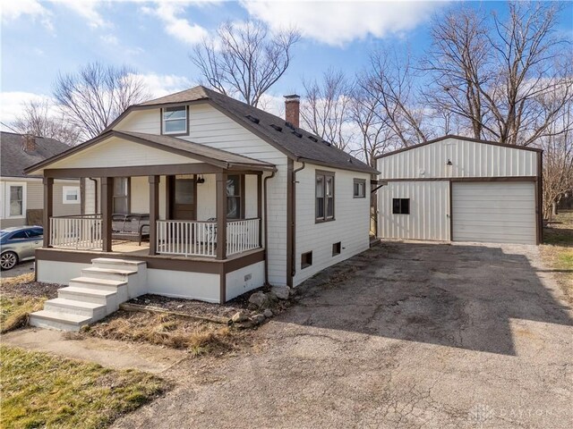 view of front of house featuring a porch, a garage, and an outbuilding