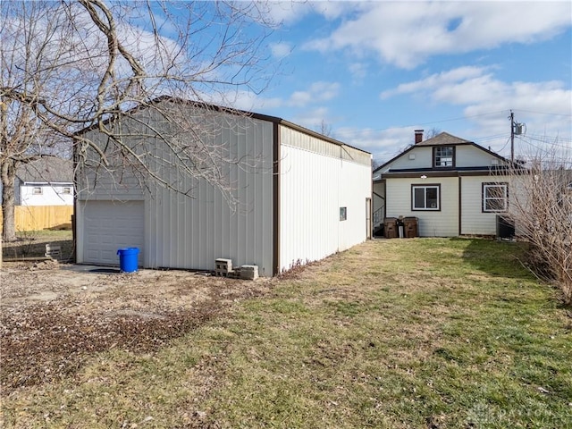 exterior space with a garage, central AC, an outbuilding, and a lawn