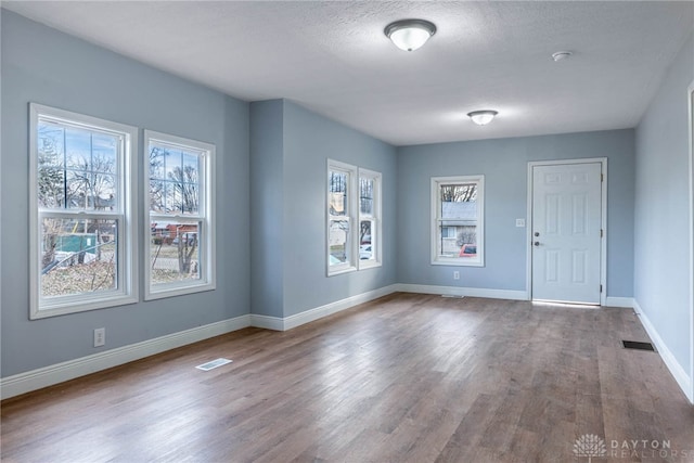 unfurnished room featuring wood finished floors, baseboards, and visible vents