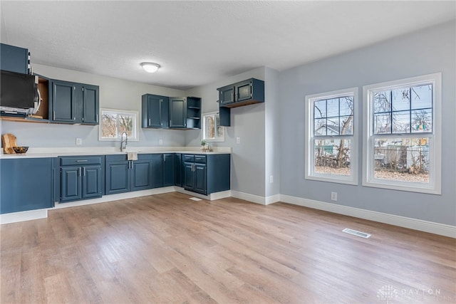 kitchen featuring sink, light hardwood / wood-style flooring, a textured ceiling, and blue cabinets