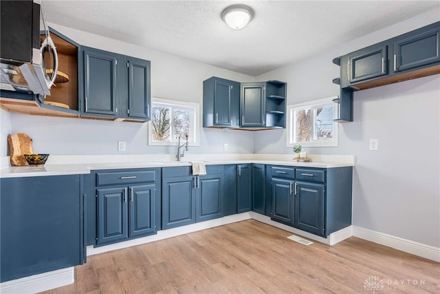 kitchen featuring plenty of natural light, light hardwood / wood-style floors, and blue cabinets