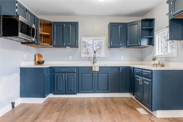 kitchen with sink, light hardwood / wood-style flooring, and blue cabinets