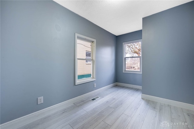 empty room featuring a textured ceiling and light wood-type flooring