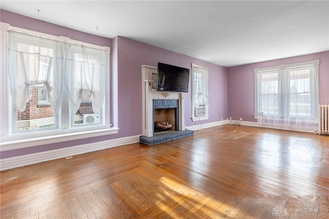 unfurnished living room featuring a fireplace, radiator heating unit, baseboards, and hardwood / wood-style floors