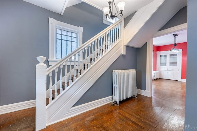 stairway featuring parquet flooring, radiator heating unit, and a notable chandelier