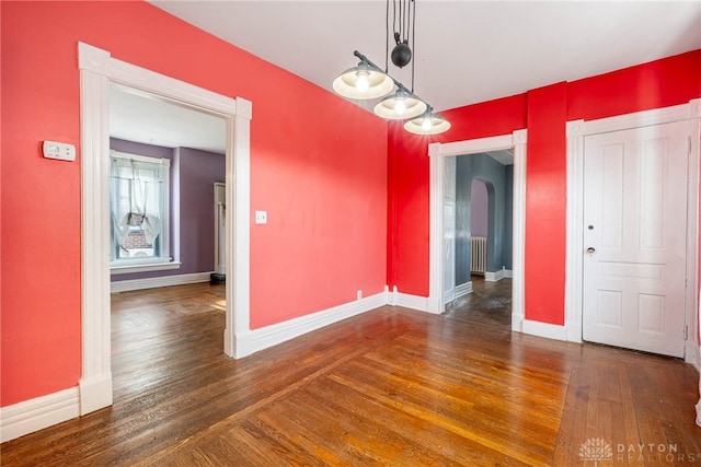 unfurnished dining area with dark hardwood / wood-style flooring and radiator heating unit