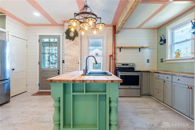 kitchen featuring wood counters, sink, hanging light fixtures, appliances with stainless steel finishes, and light hardwood / wood-style floors