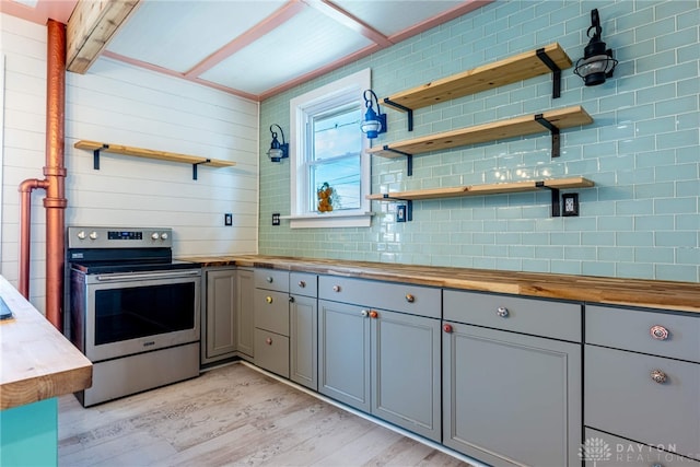 kitchen featuring stainless steel electric range, gray cabinets, light hardwood / wood-style flooring, tasteful backsplash, and wood counters