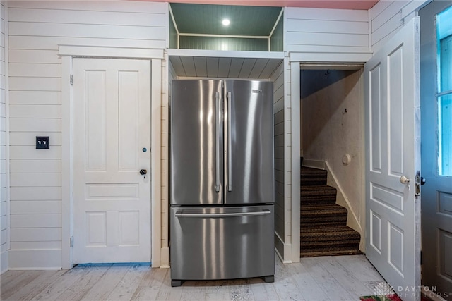 kitchen featuring wooden walls, high quality fridge, and light wood-type flooring