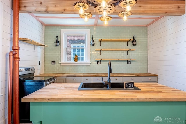 kitchen with wooden walls, beamed ceiling, butcher block counters, sink, and backsplash