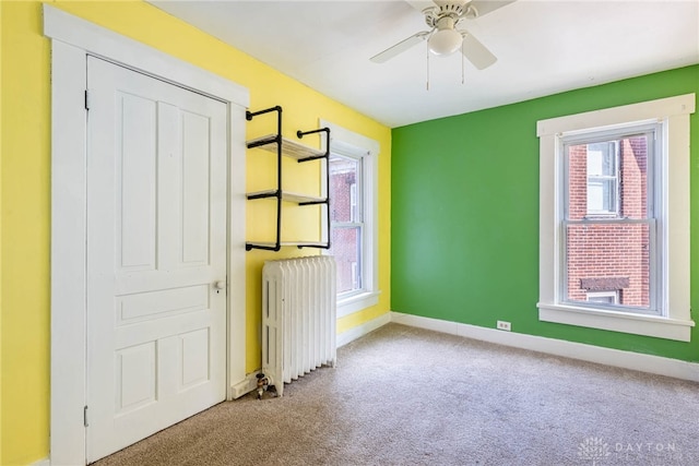 unfurnished bedroom featuring ceiling fan, carpet flooring, and radiator