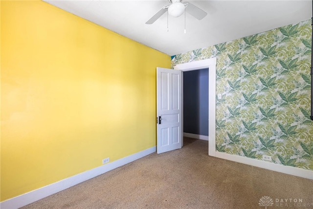 carpeted spare room with baseboards, a ceiling fan, and wallpapered walls