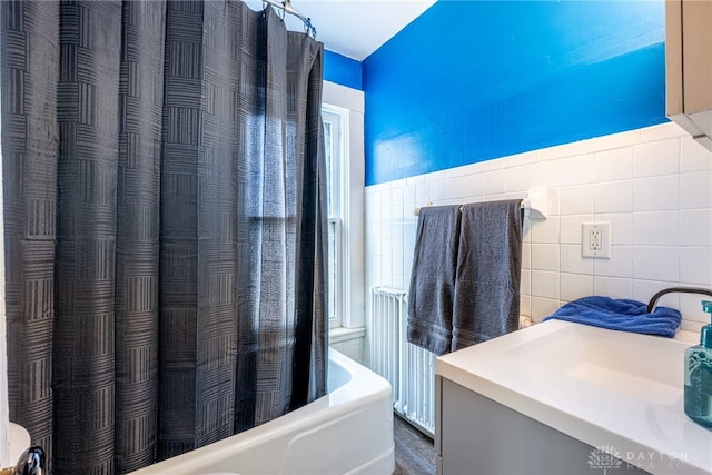 bathroom with radiator heating unit, sink, and tile walls