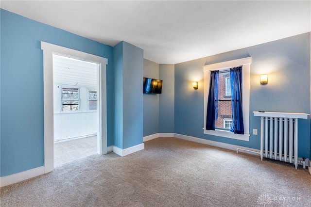 spare room with radiator, carpet floors, and a wealth of natural light