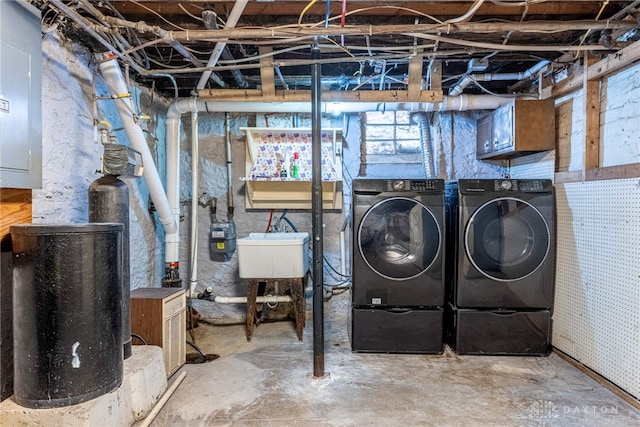 basement featuring washing machine and clothes dryer, electric panel, and sink