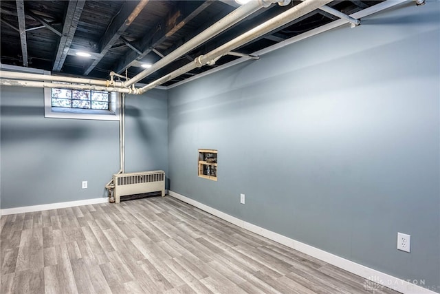 below grade area featuring baseboards, wood finished floors, and radiator heating unit