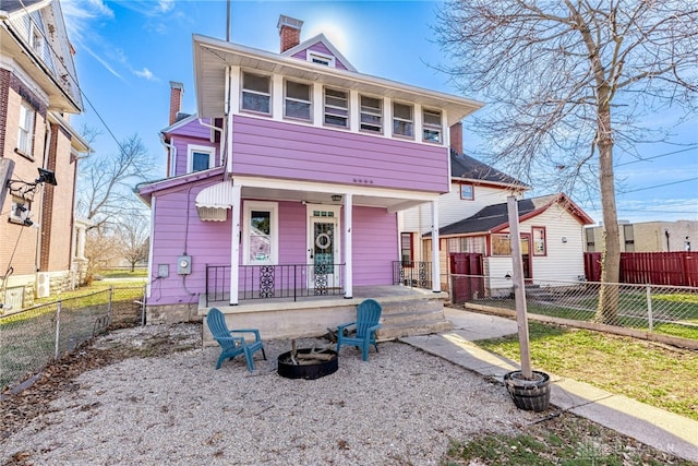 view of front of home featuring an outdoor fire pit, covered porch, a chimney, and fence