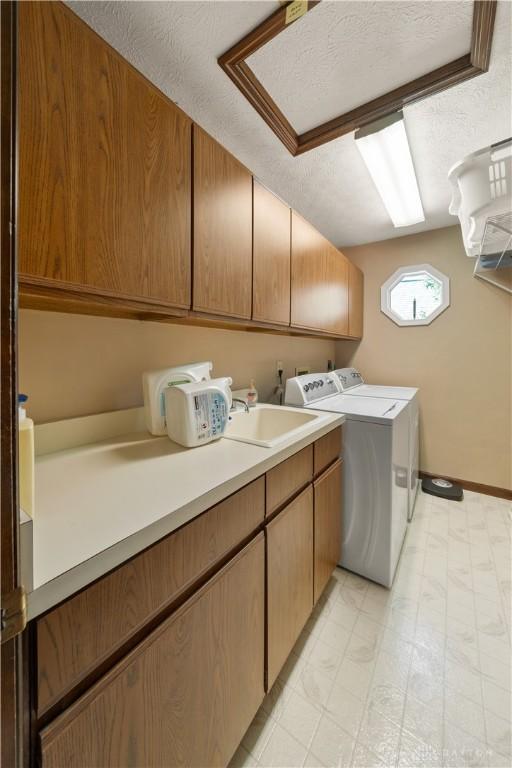 laundry room with cabinets, a textured ceiling, and washer and clothes dryer