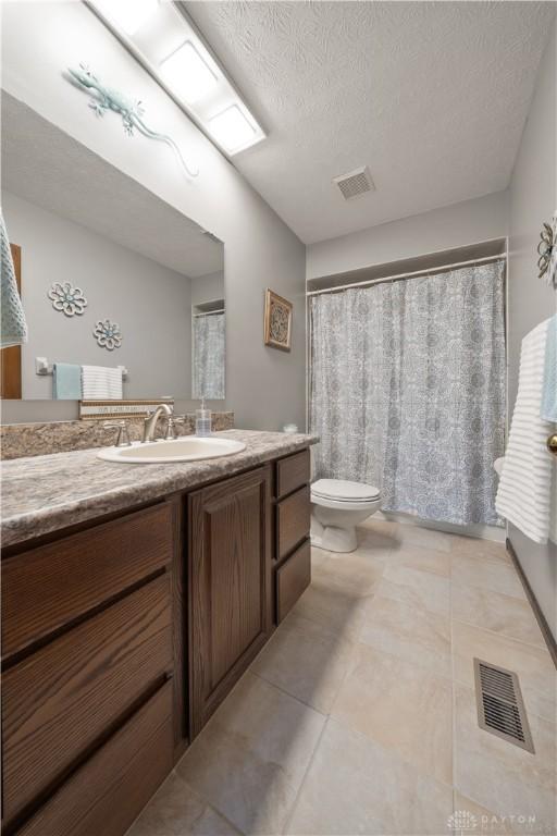 bathroom featuring tile patterned floors, vanity, toilet, and a textured ceiling