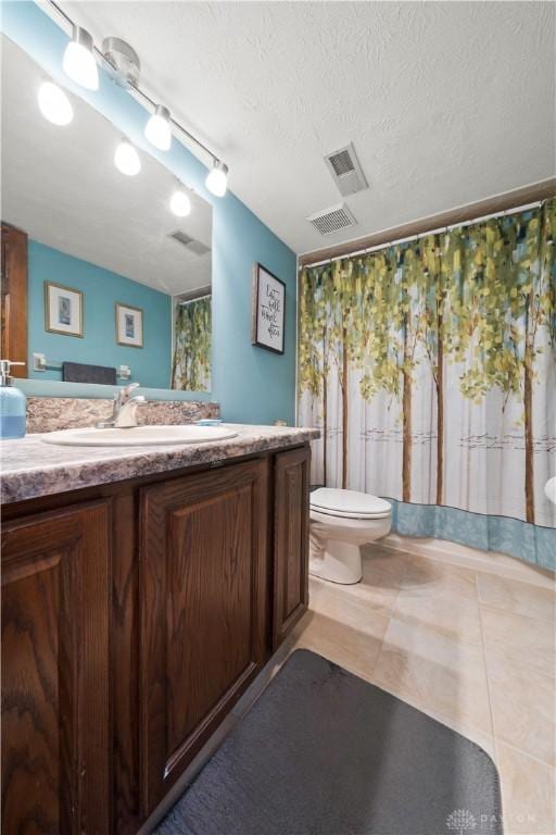 bathroom with vanity, a textured ceiling, tile patterned floors, and toilet