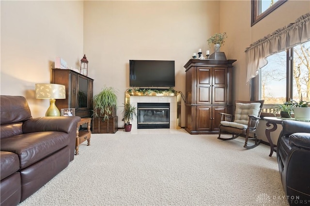 carpeted living room with a towering ceiling and a tiled fireplace