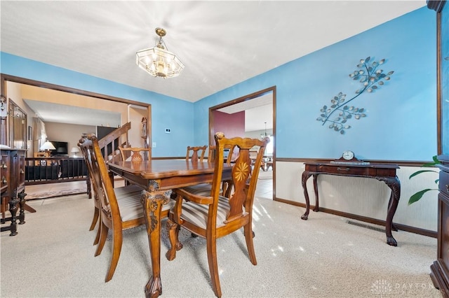 dining area with an inviting chandelier and light carpet