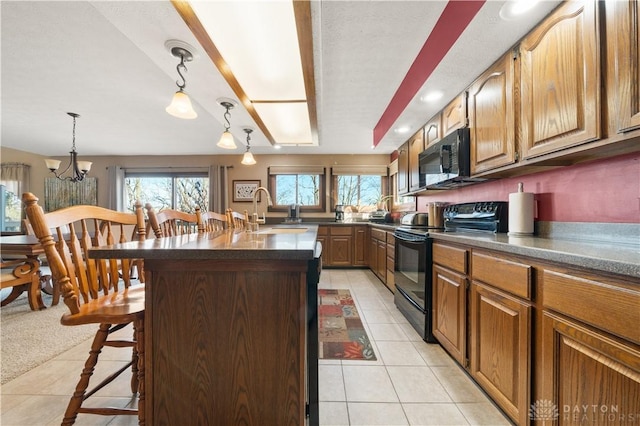 kitchen featuring sink, a breakfast bar, hanging light fixtures, black appliances, and a kitchen island