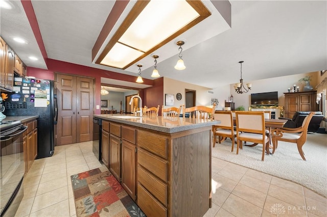 kitchen featuring sink, a center island with sink, black appliances, light tile patterned flooring, and decorative light fixtures