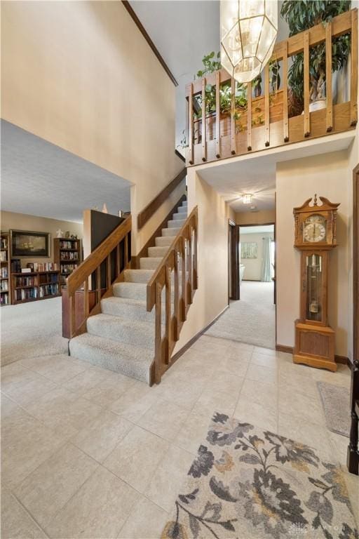 stairway with a towering ceiling, carpet floors, and a notable chandelier