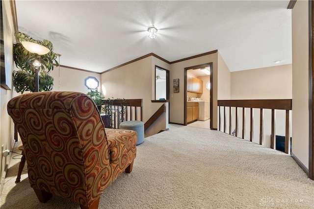 sitting room featuring light colored carpet, ornamental molding, and washer and clothes dryer