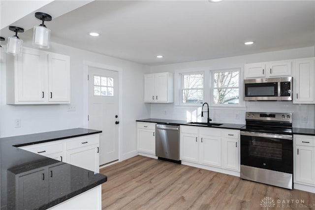 kitchen with stainless steel appliances, decorative light fixtures, sink, and white cabinets