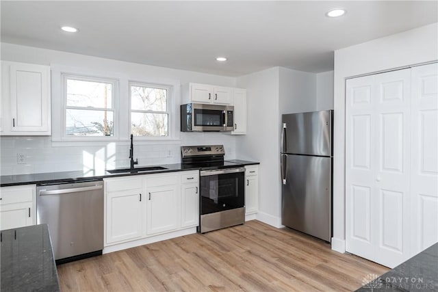 kitchen featuring appliances with stainless steel finishes, sink, white cabinets, and light hardwood / wood-style floors