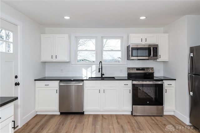 kitchen featuring white cabinetry, appliances with stainless steel finishes, sink, and light hardwood / wood-style flooring