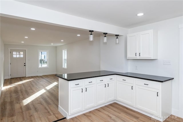 kitchen with light hardwood / wood-style flooring, kitchen peninsula, and white cabinets